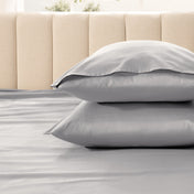 Two pillows stacked on a bed with a beige headboard.