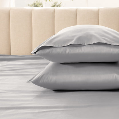 Two pillows stacked on a bed with a beige headboard.