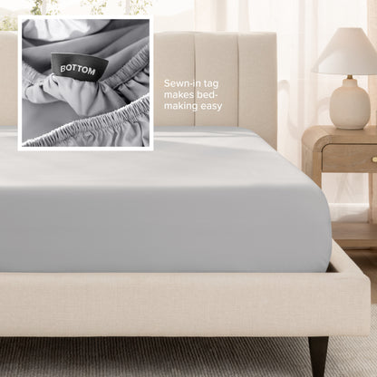 A fitted bed sheet shown on a bed. Text on the image says the sewn-in tag makes bed-making easy.