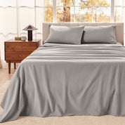 Bedroom with a neatly made bed  wooden nightstand, and window with autumn view.