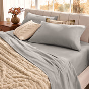 Neatly made bed with organic flannel sheets  and a beige blanket in a bright bedroom.