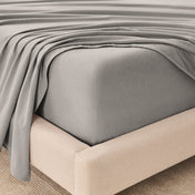 Fitted sheet and top sheet on a mattress with a beige bed frame