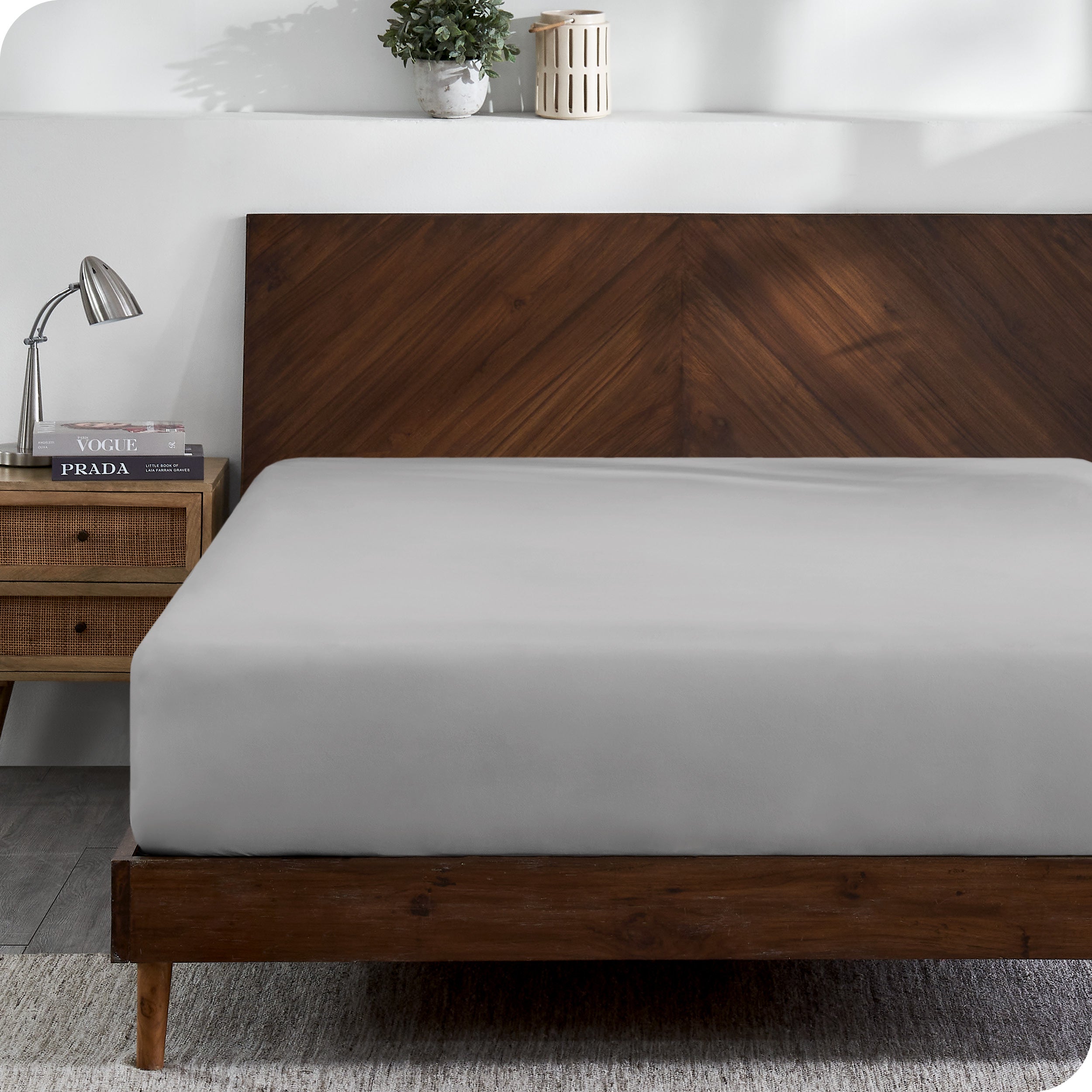 A modern wooden bed frame with a fitted sheet on the mattress