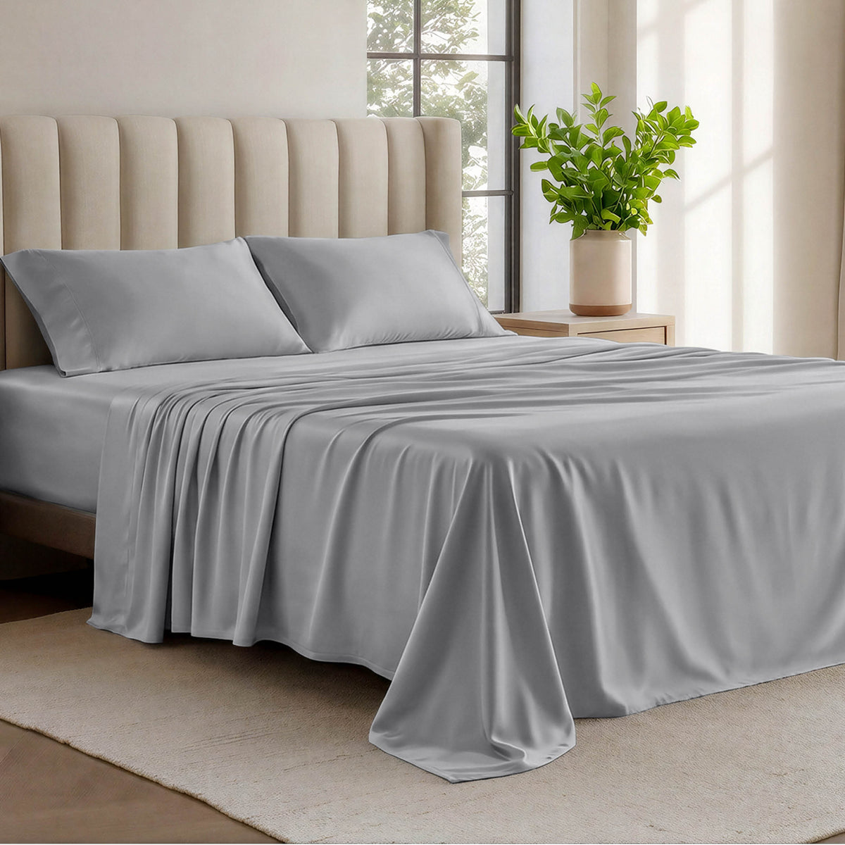 Organic cotton jersey sheets on a bed with a wicker headboard in a room with plants and a lamp.