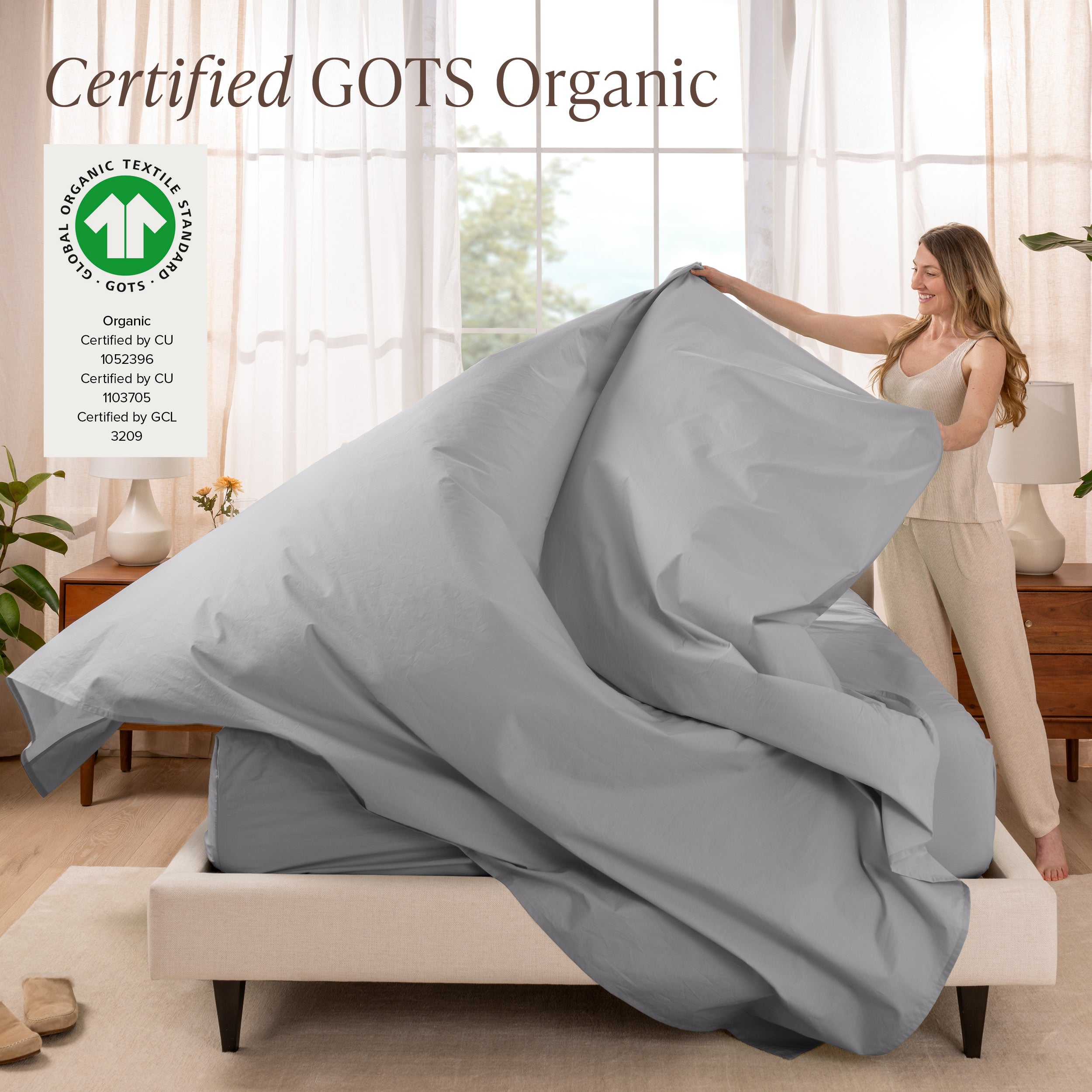 A woman is making a bed with organic cotton percale sheets