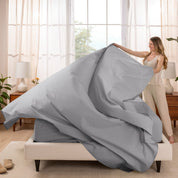 Woman putting a sheet set on a bed in a bright bedroom.