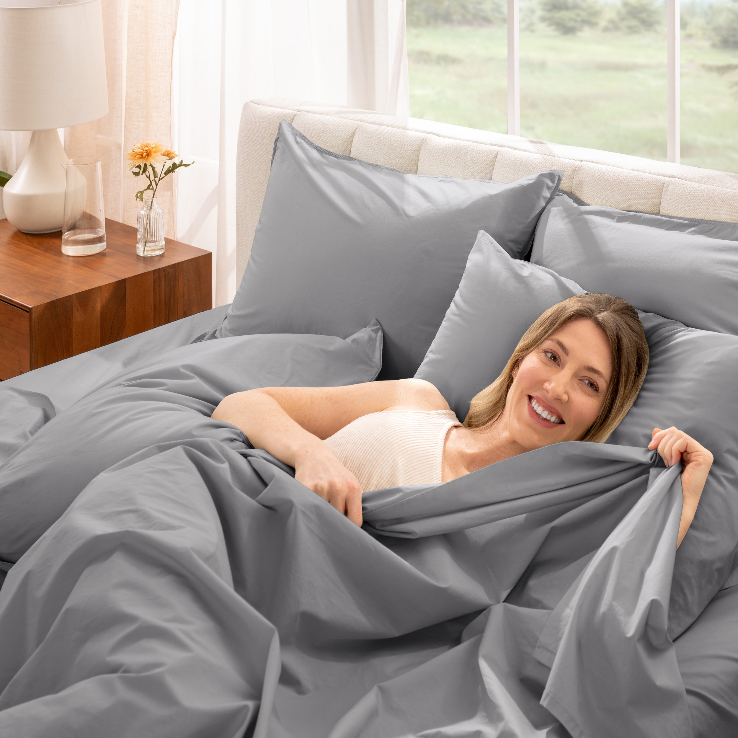 A woman is lying on a bed make with percale sheets and pillowcases