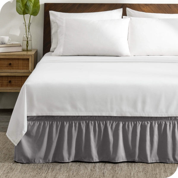 A wrap around bed skirt on a mattress with white bedding