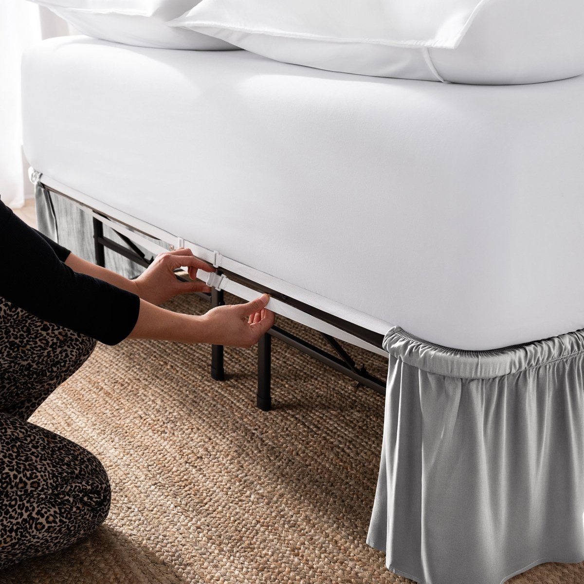 Adjustable bed skirt on a bed showing the elastic strap.