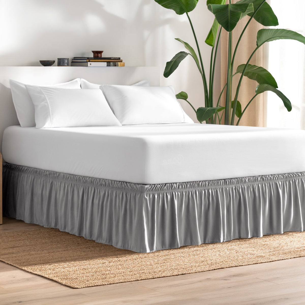 Bed with bed skirt, white bedding, and a plant in a room.
