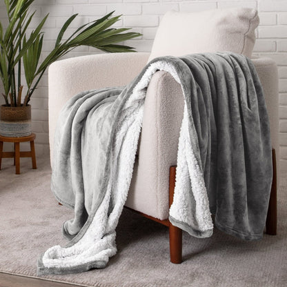 Sherpa blanket draped over a chair in a cozy living room setting with a plant and white brick wall.