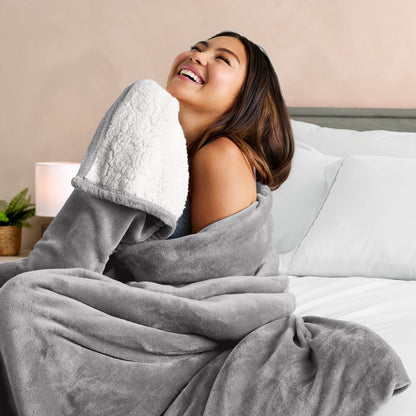 Woman wrapped in a blanket and smiling in bed.