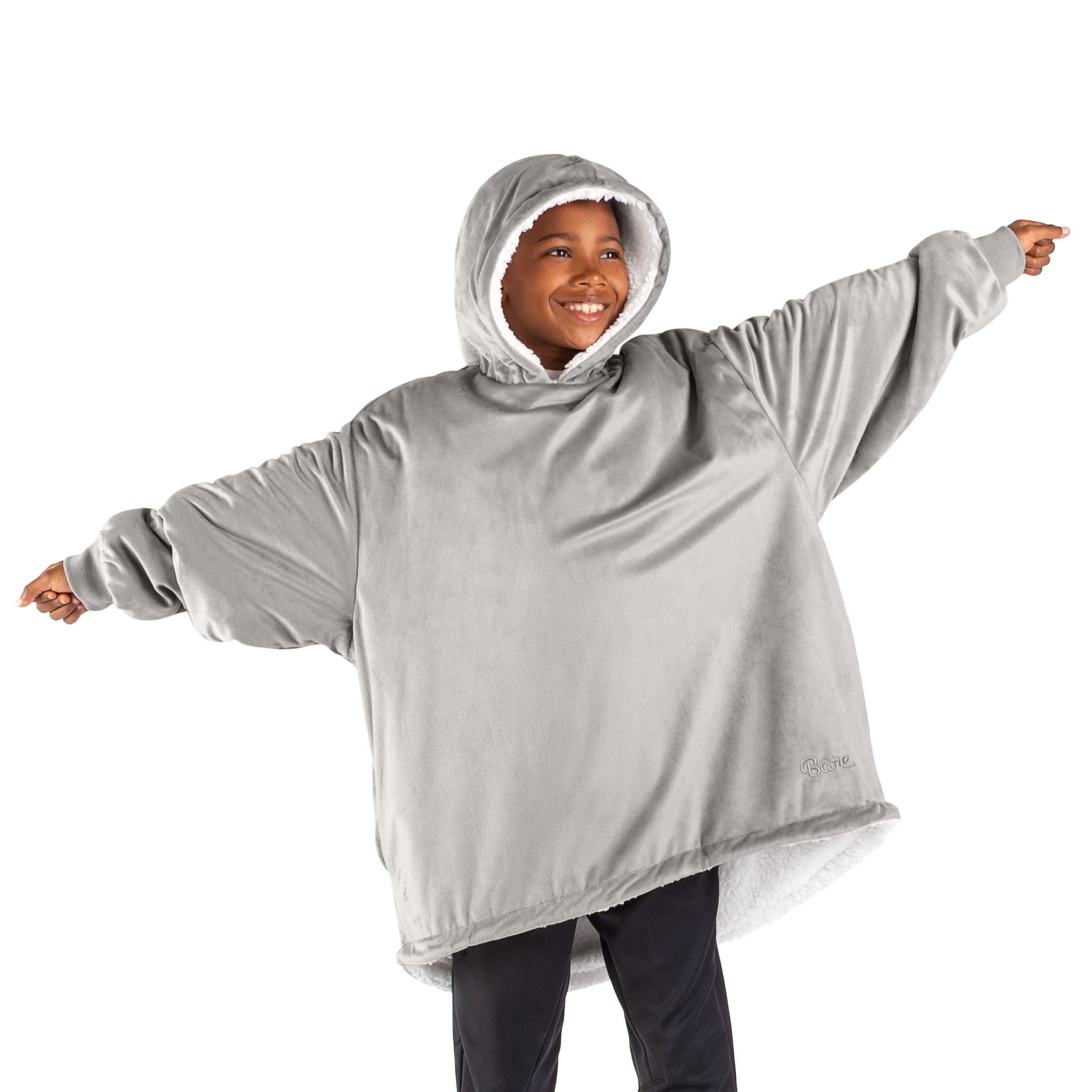 A boy standing with his arms stretched out while wearing a wearable blanket