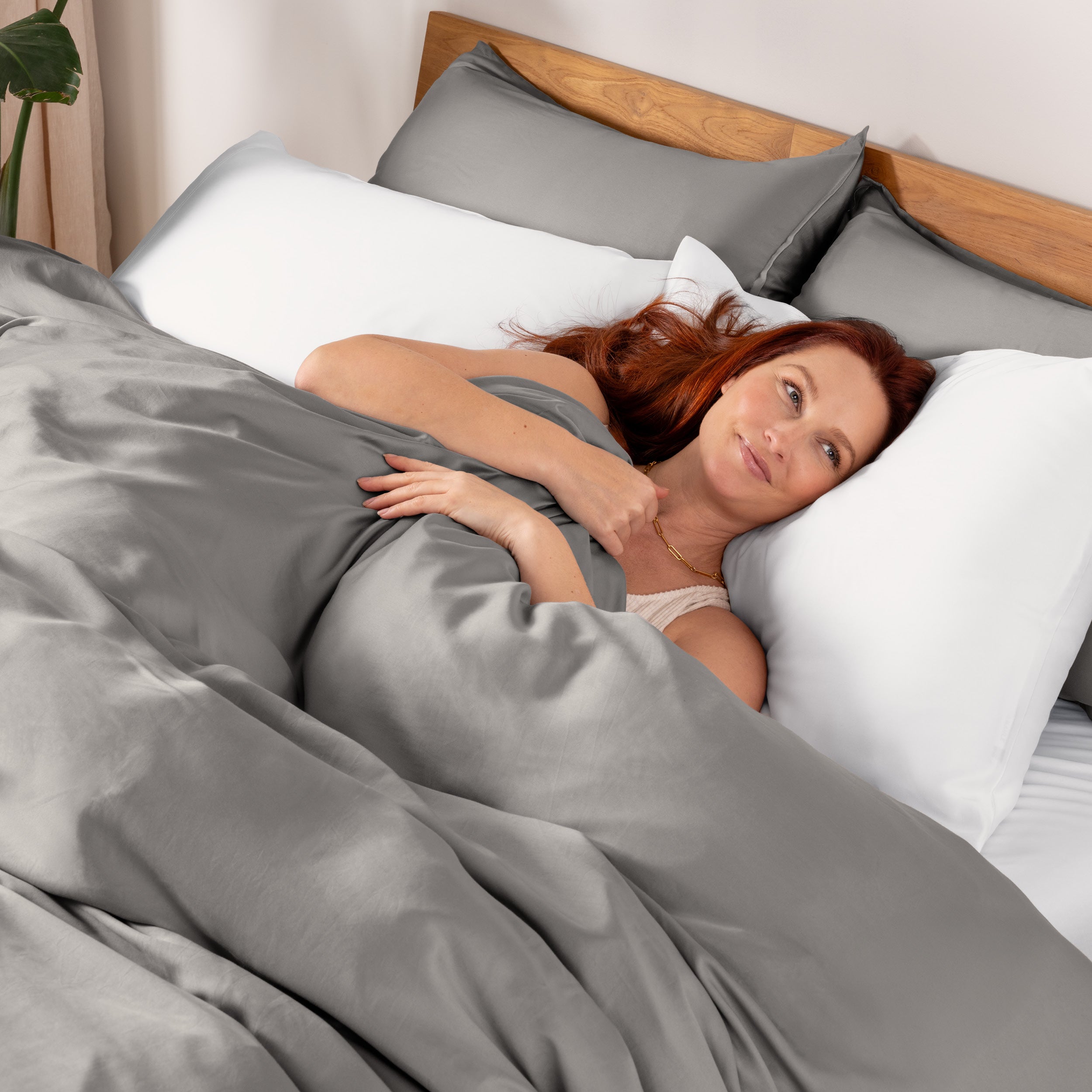 Woman lying in bed under duvet cover.