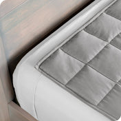 Close up of a weighted blanket on top of a bed made with white sheets