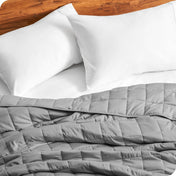 Close up of a weighted blanket on a bed next to pillows