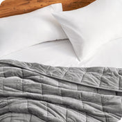 Close up of a weighted blanket on a bed next to pillows