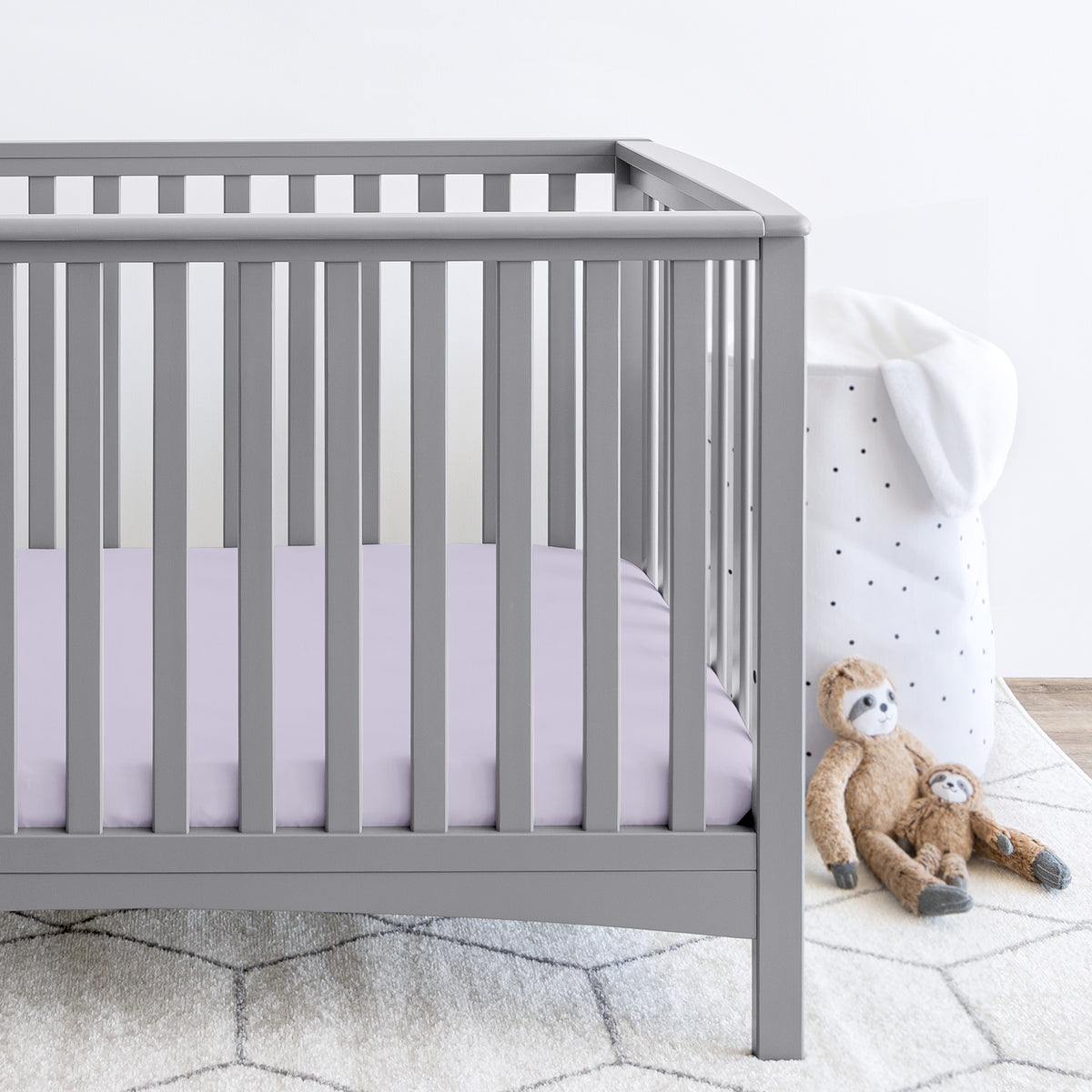 Gray crib with stuffed animals on the floor next to it