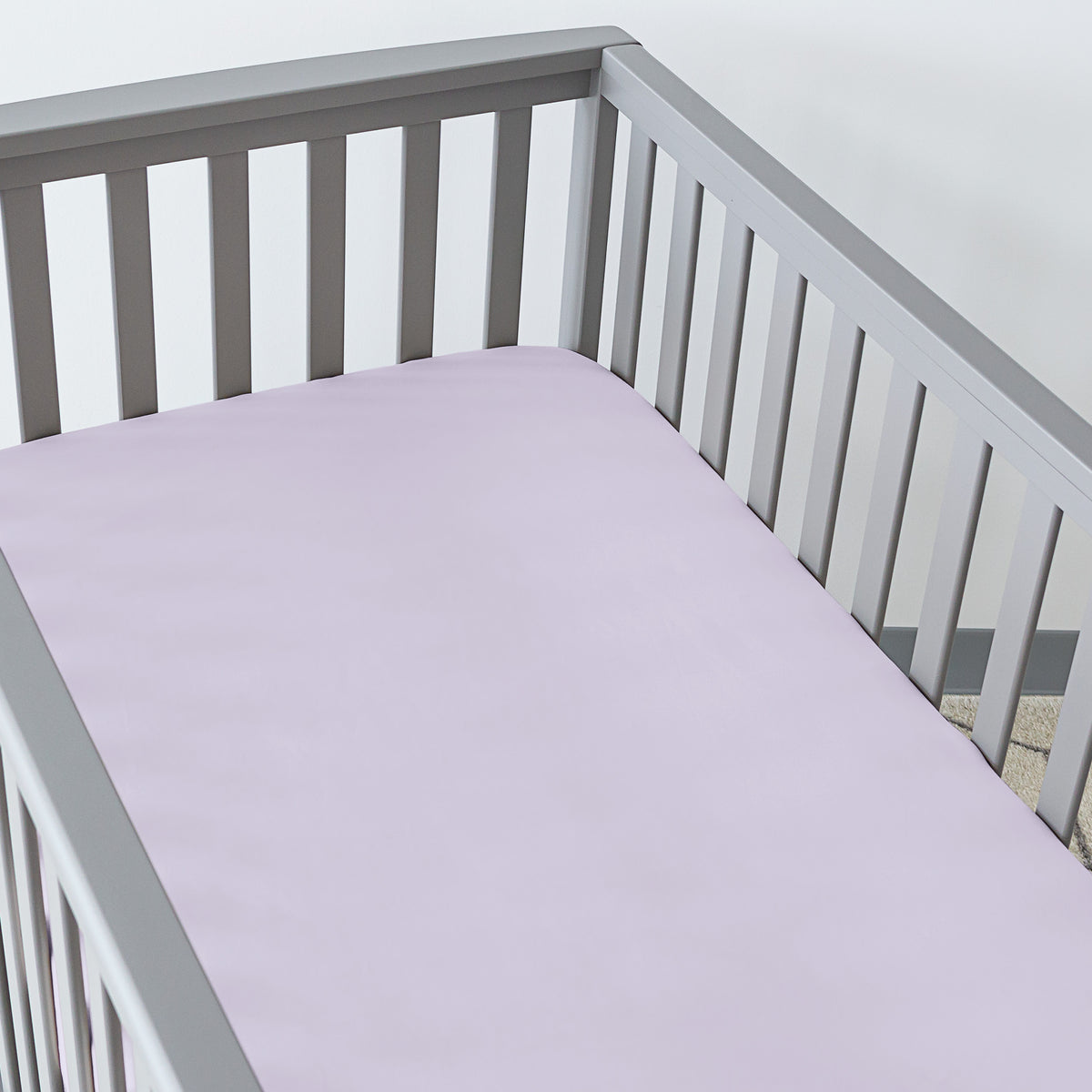 Gray crib with a fitted sheet on the mattress