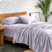 Bed with microfiber sheets against a white brick wall