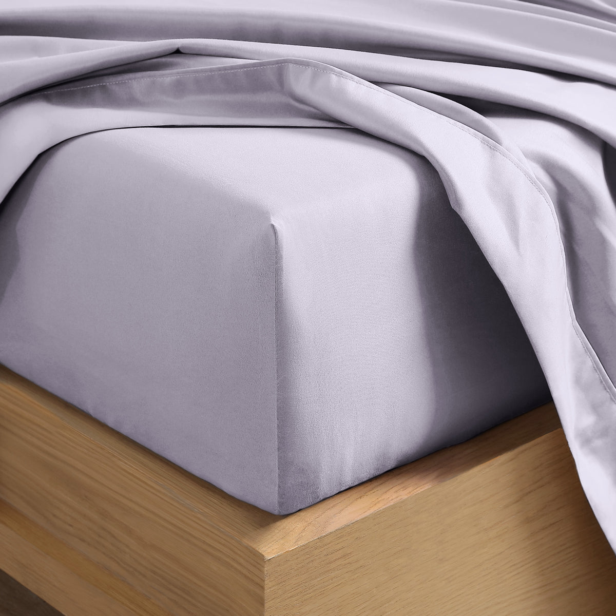 Close up of the corner of a mattress with a fitted sheet and flat sheet on it