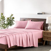 A bamboo sheet set draped over a bed with a wooden bed frame