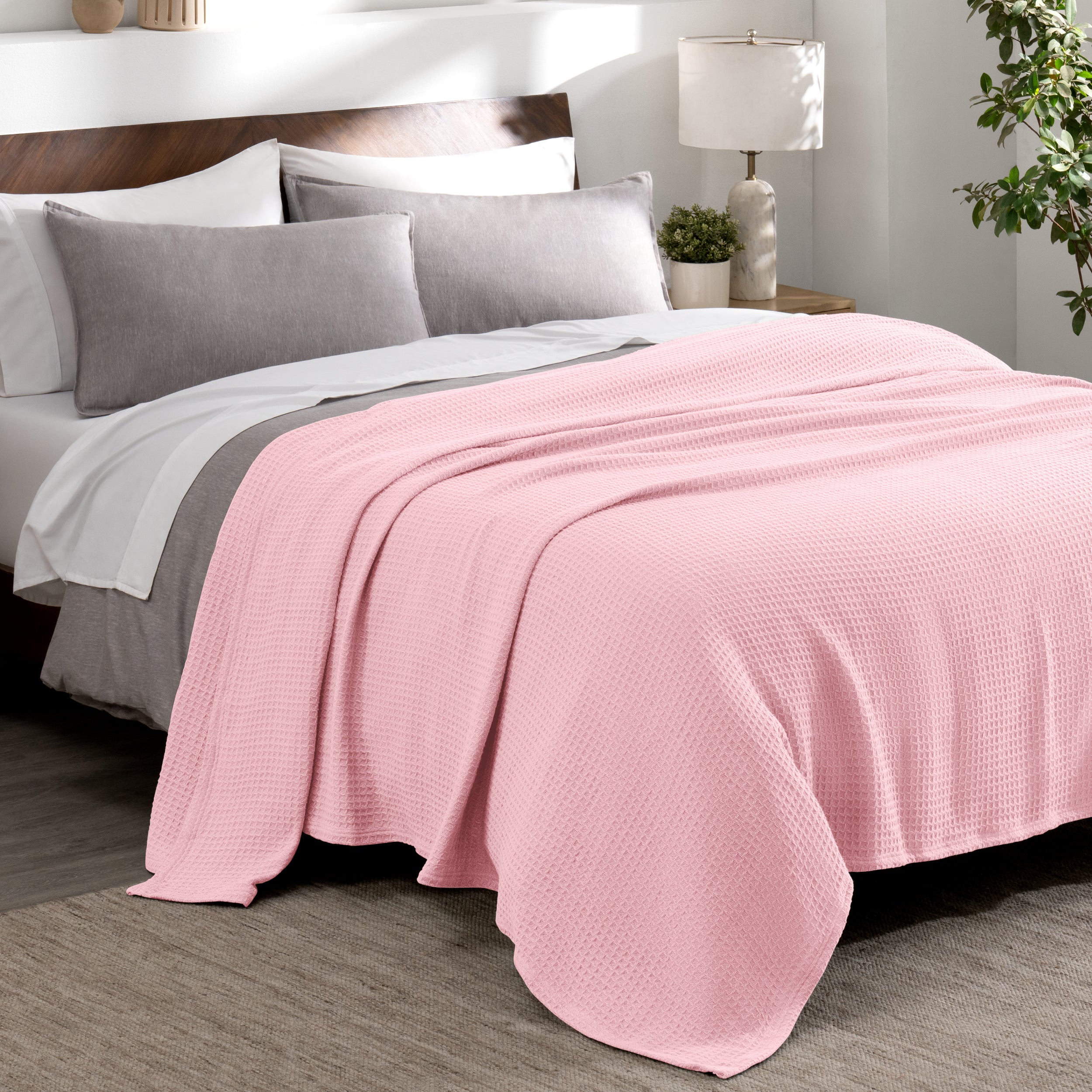 Cotton waffle blanket draped over a bed with pillows in a bedroom setting.