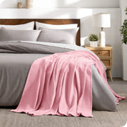 A cotton waffle blanket is on the corner of a bed. It is hanging down the side and end of the bed.
