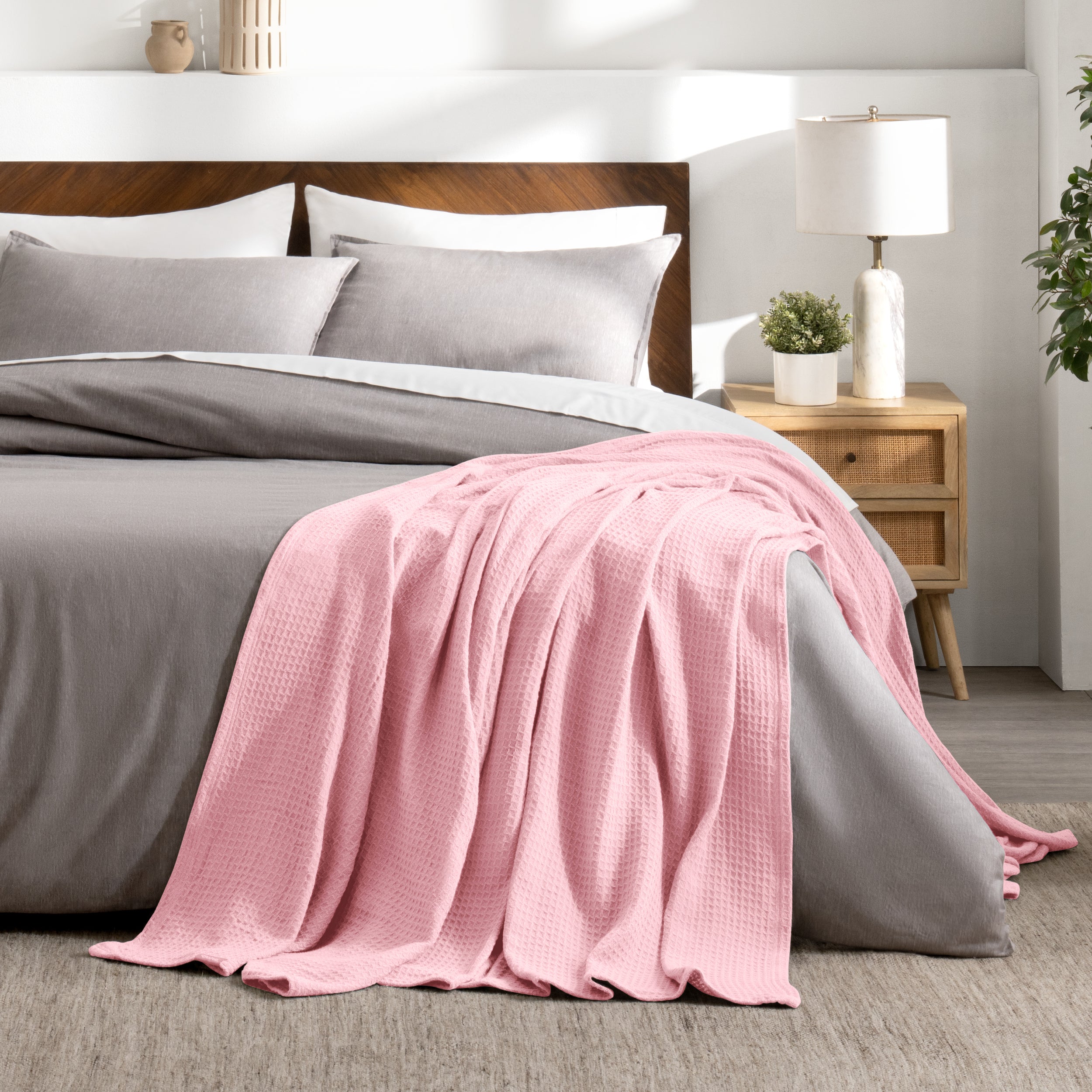 Bed with gray bedding and a throw blanket in a bedroom setting.
