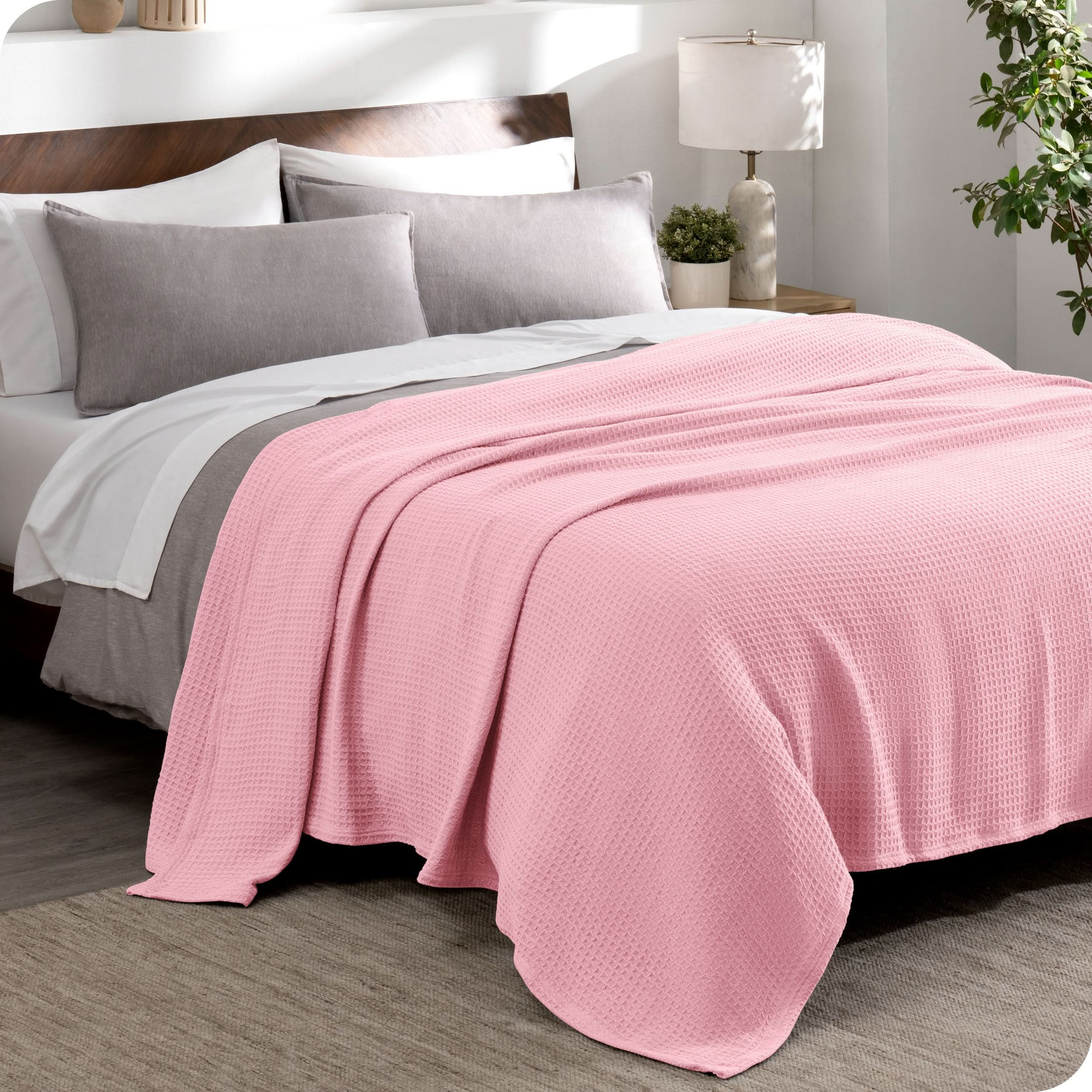 A cotton waffle blanket draped over the top of a bed made with a duvet set