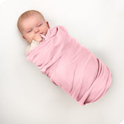 A baby swaddled in a receiving blanket