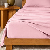 Bed with flannel bedding and wooden headboard and nightstand next to it.