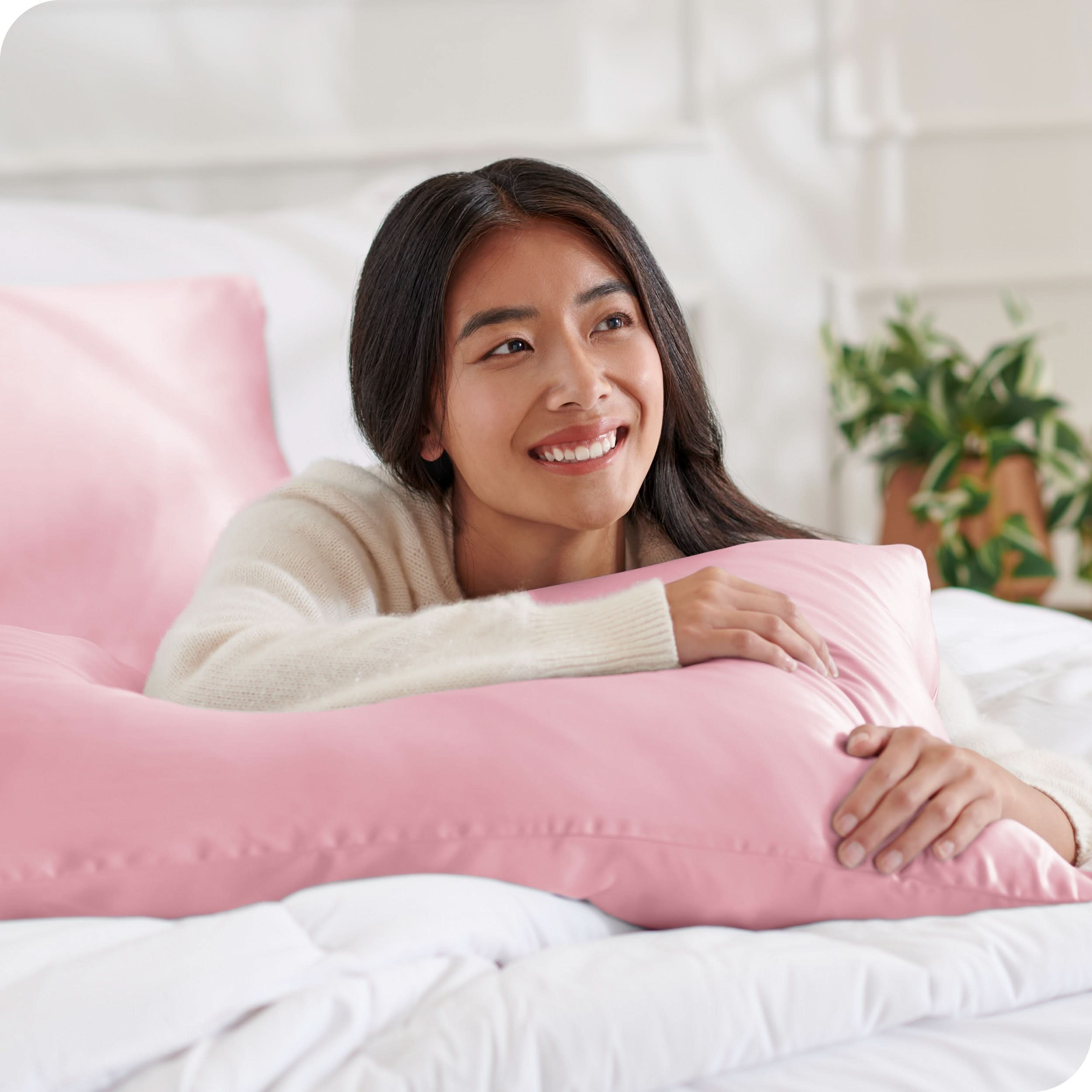 A woman on a bed with a silk pillowcase covered pillow