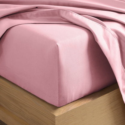 A close-up of a fitted sheet covering the corner of a bed frame, with matching top sheet draped over it.