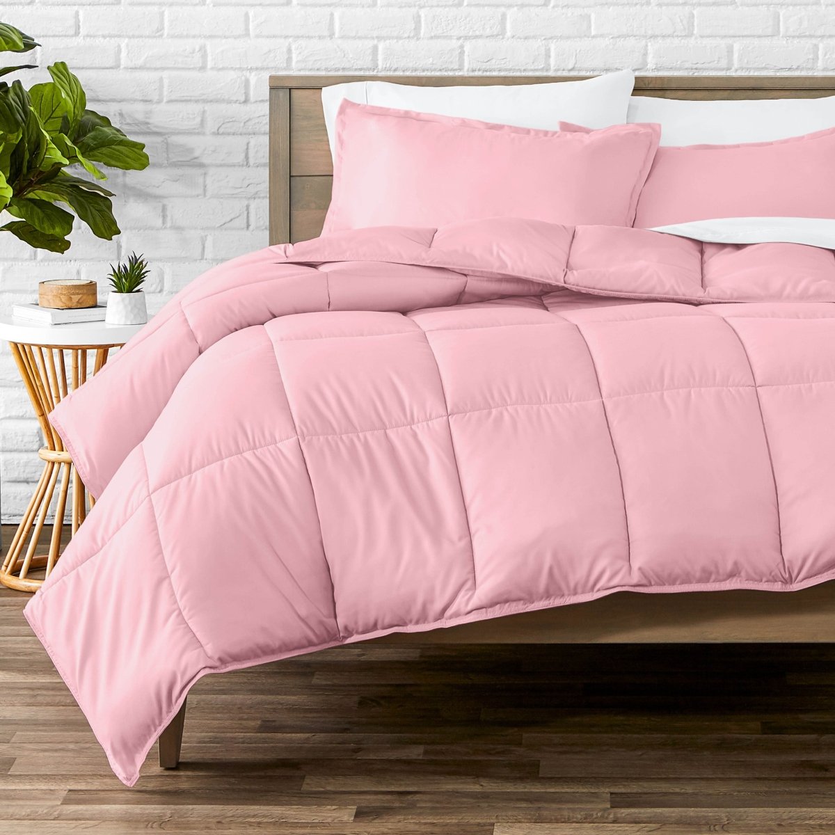 Comforter set on a bed with a white brick wall and plant in the background