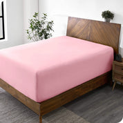 A diagonal view of a bed with just a fitted sheet on it