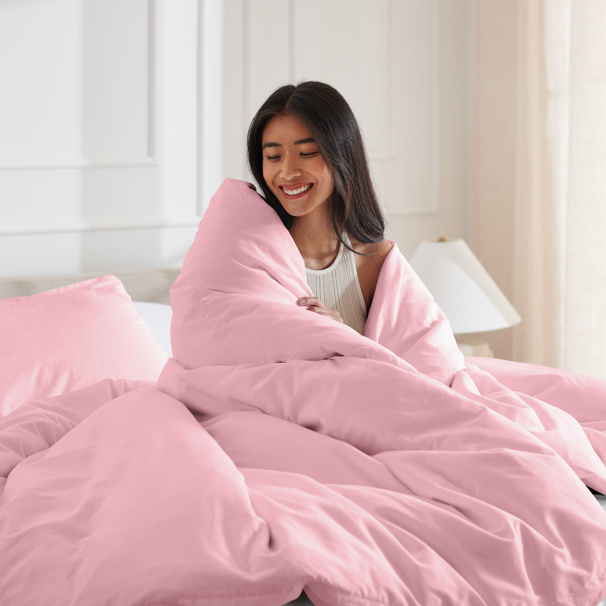 Woman smiling under duvet cover set in a bedroom setting