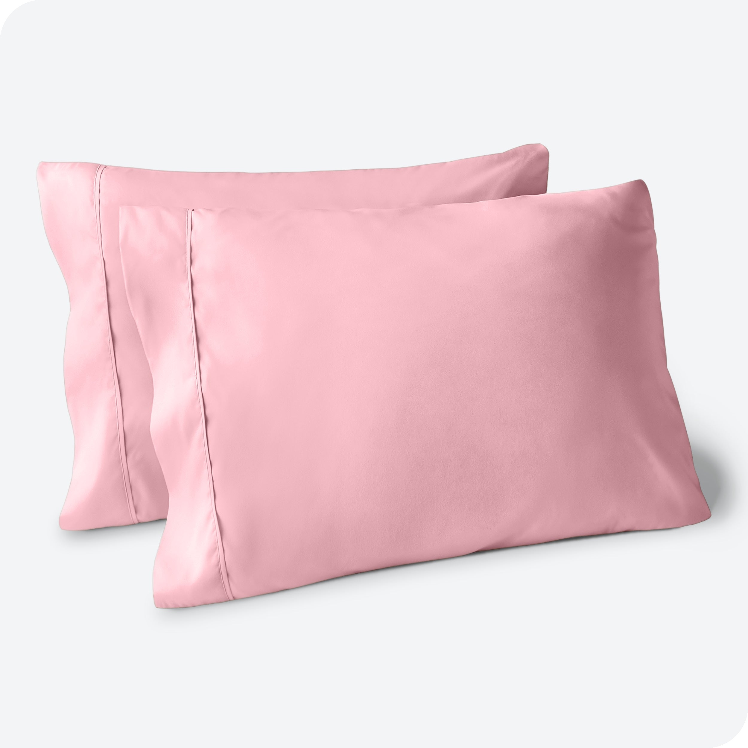 Two pillows on a white background with pink pillowcases on them