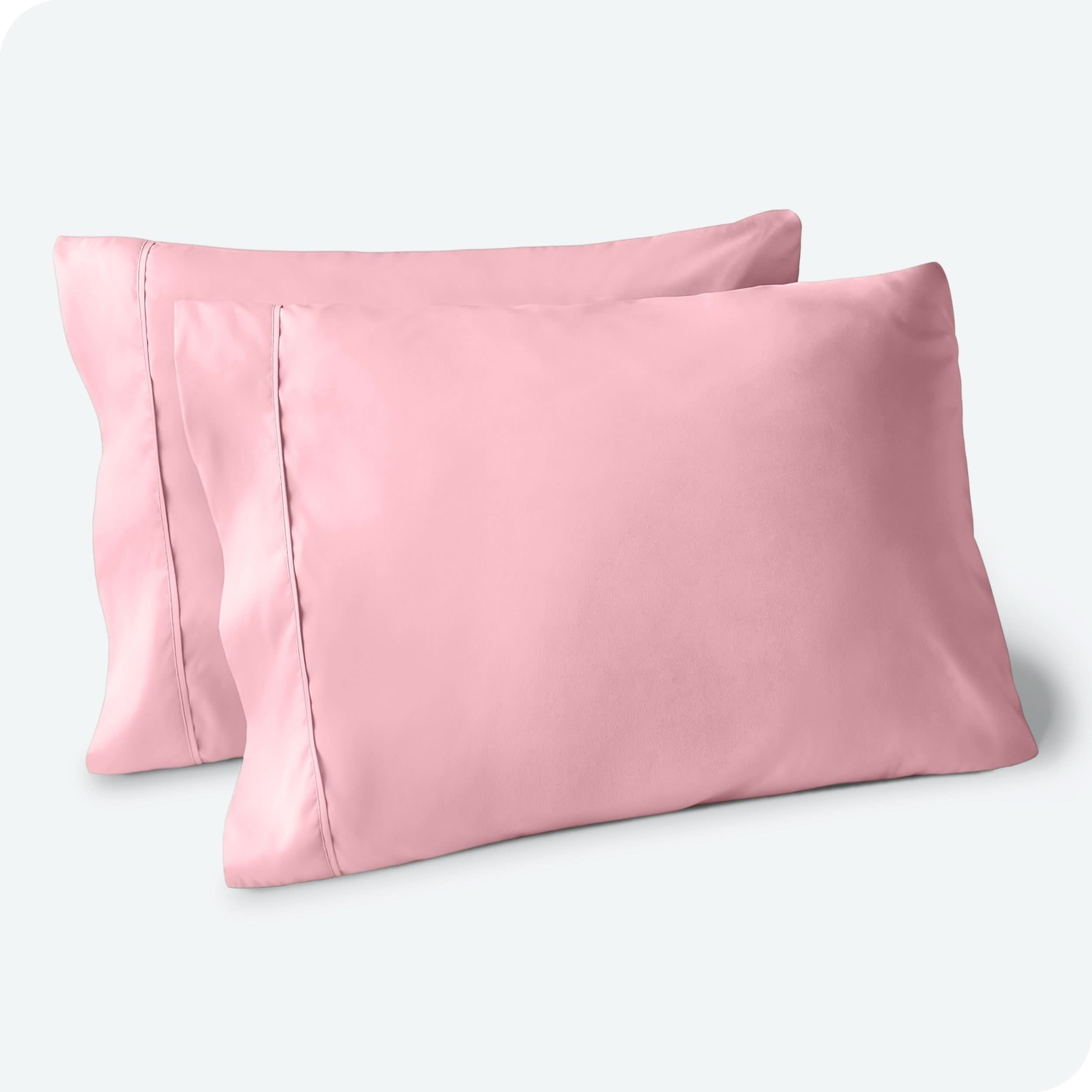 Two pillows on a white background with pink pillowcases on them