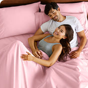 A couple is relaxing in bed with pillows behind them