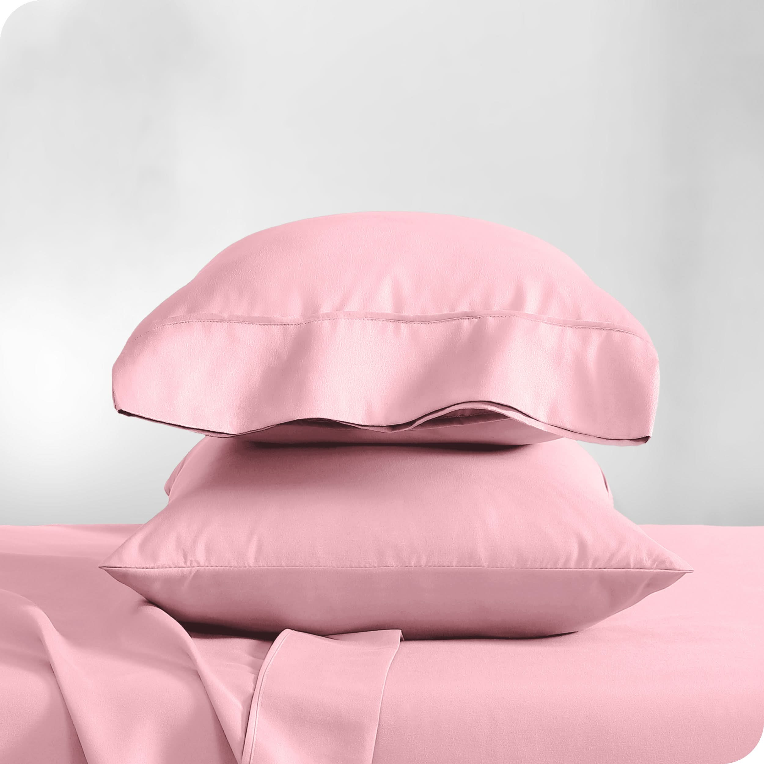 Two pillowcases on pillows stacked on a bed with matching sheets