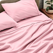 Bed sheets and pillows on a bed with a plant in the background
