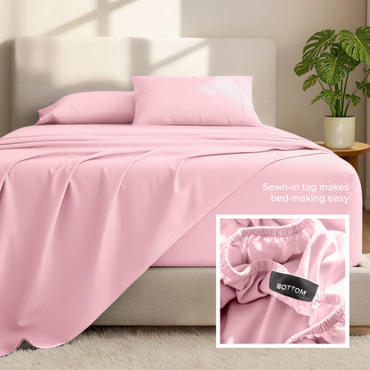Bed sheets and pillows on a bed with a plant in the background