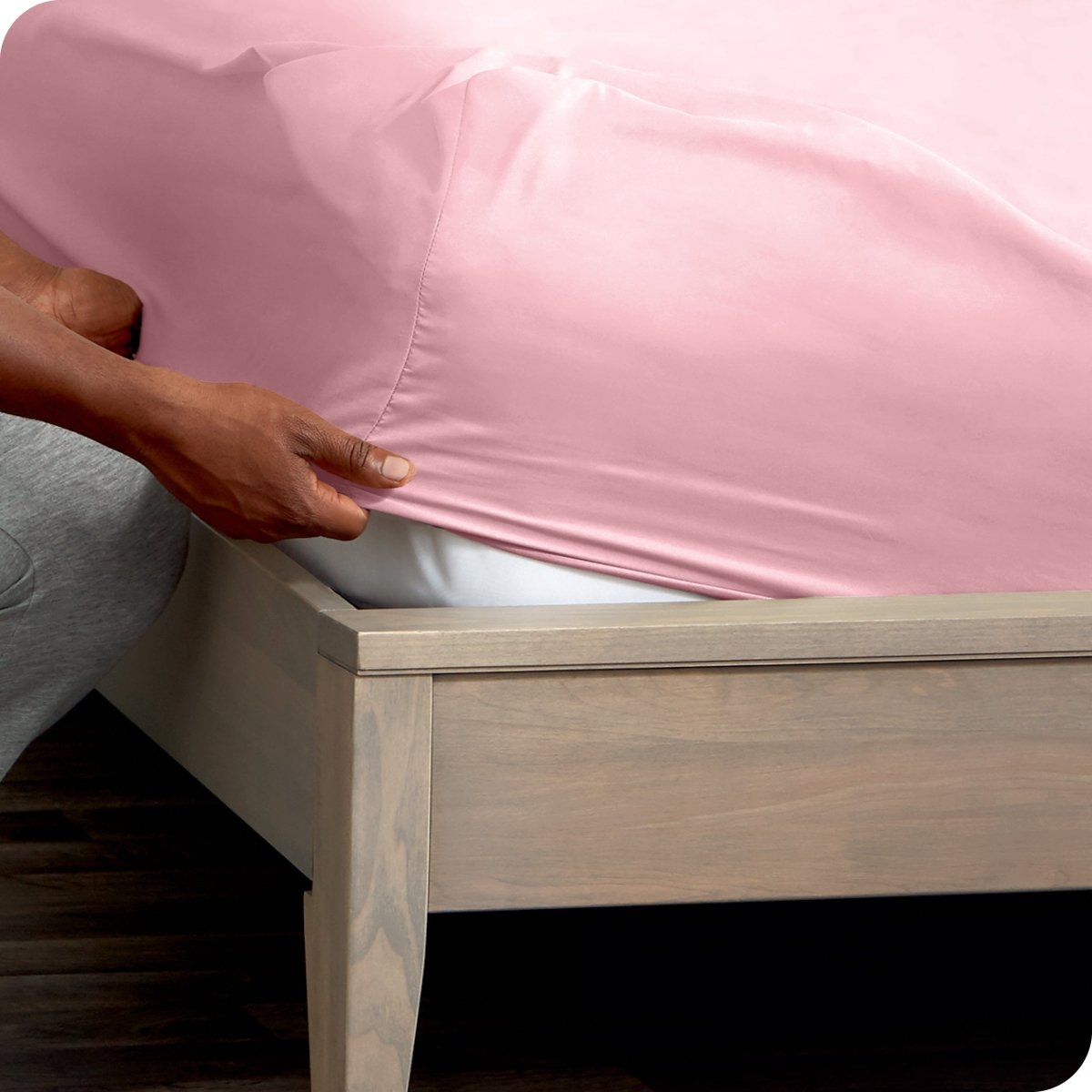 Person adjusting a fitted sheet on a mattress