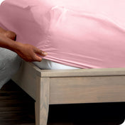 Person adjusting a fitted sheet on a mattress