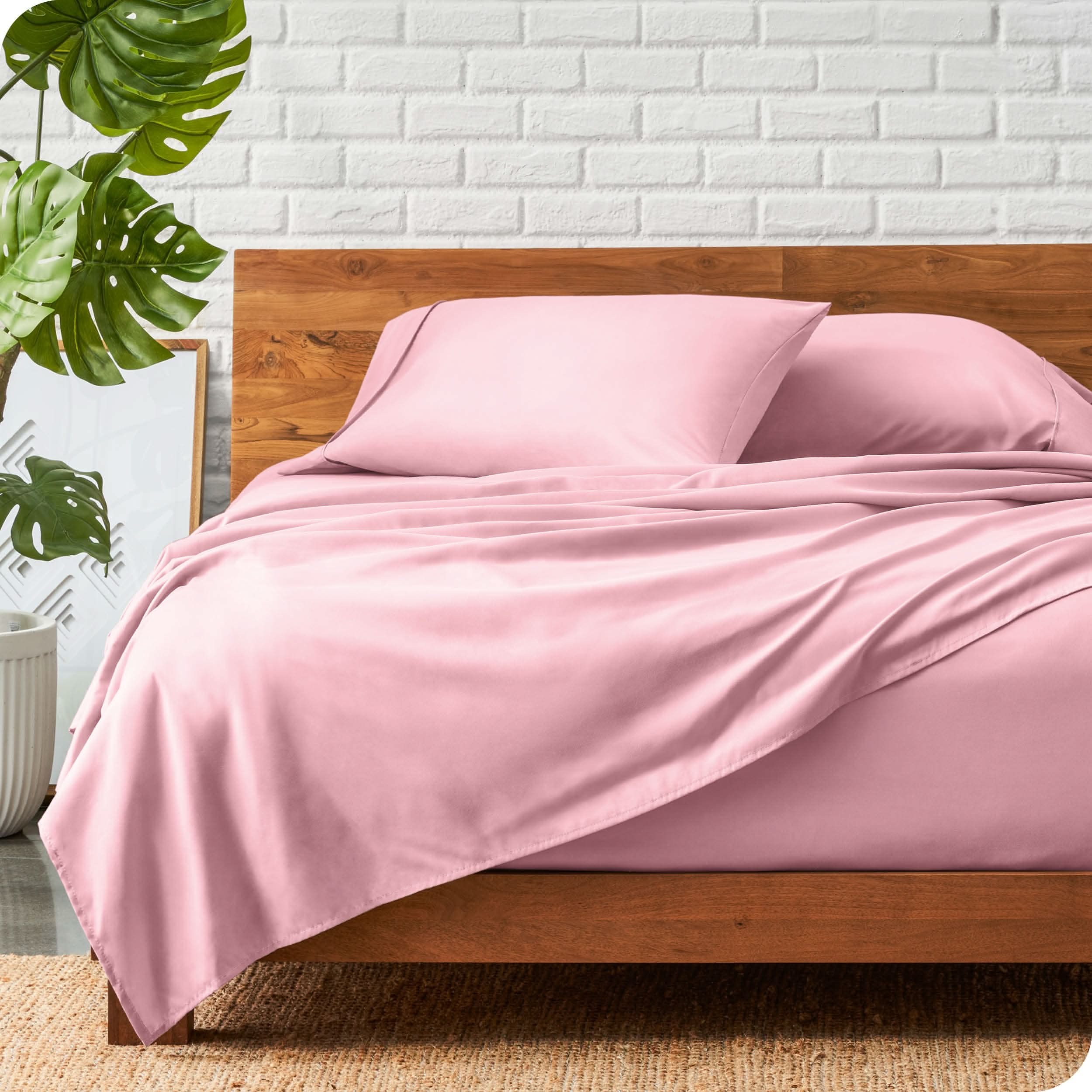 A wooden bed frame with a microfiber sheet set on the mattress.