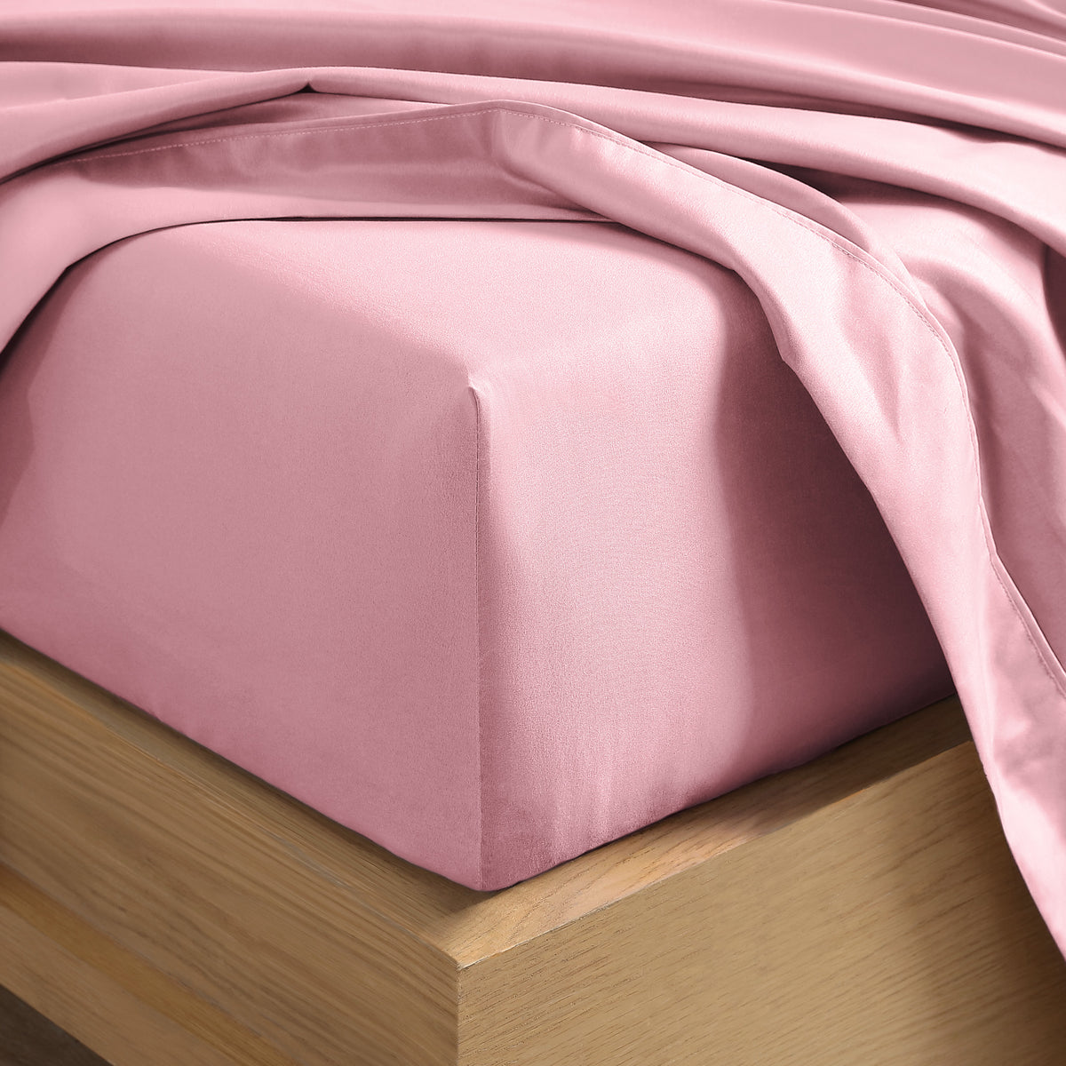 Close up of the corner of a mattress with a fitted sheet and flat sheet on it