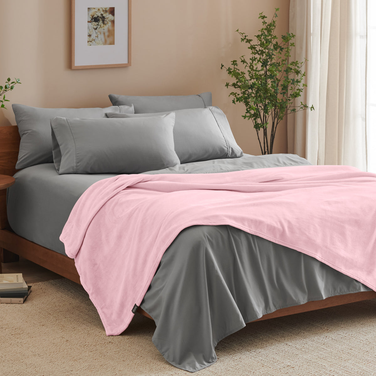 A bed made with grey sheets and a microplush blanket
