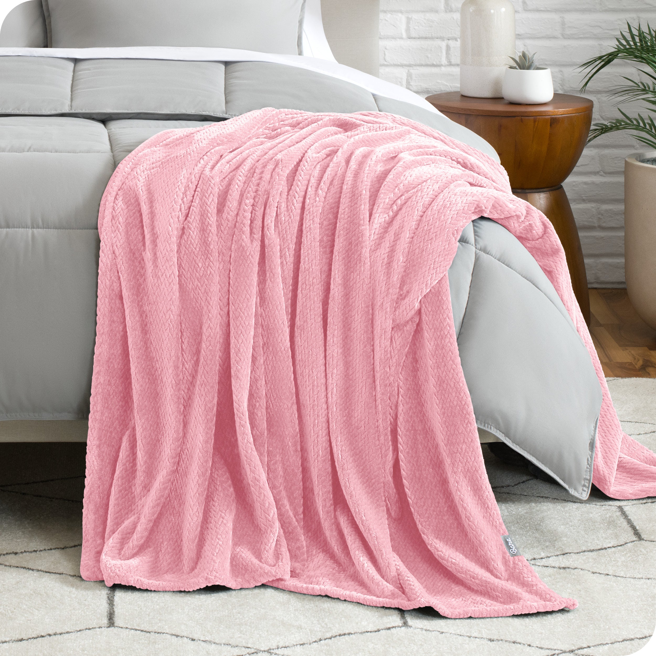 A microplush blanket is draped over the side and bottom of a neatly made bed.