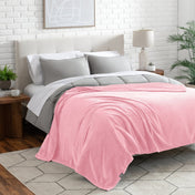 Neatly made bed with a blanket draped over the end of the bed